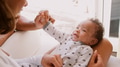 Mother Sitting On Chair In Bedroom Holding Smiling Baby Son - PhotoDune Item for Sale