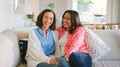 Portrait Of Smiling Mature Mother And Adult Daughter Sitting On Sofa At Home Together - PhotoDune Item for Sale