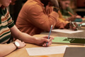 Young Woman Writing Notes during Group Study Session Indoors - PhotoDune Item for Sale