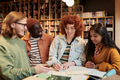 Group of Multiethnic Young People Collaborating on Project in Library Setting - PhotoDune Item for Sale