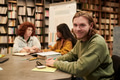 Young Man Smiling While Studying with Diverse Group in Library - PhotoDune Item for Sale