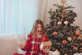 Young Woman Unwrapping Christmas Gift By Decorated Tree - PhotoDune Item for Sale