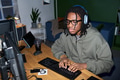 Young Black Man Wearing Headphones Using Computer While Working - PhotoDune Item for Sale
