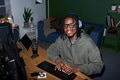 Portrait of Young Black Man Wearing Headphones Using Computer at Desk - PhotoDune Item for Sale