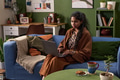 Young South Asian Woman Using Laptop While Sitting on Sofa at Home - PhotoDune Item for Sale