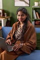 Portrait of Young South Asian Woman Smiling While Using Laptop Indoors - PhotoDune Item for Sale