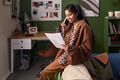 Young South Asian Woman Smiling While Talking on Phone and Reading Document - PhotoDune Item for Sale