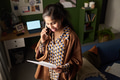 Young South Asian Woman Reviewing Paperwork While Having Phone Conversation - PhotoDune Item for Sale