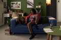 Young Black Man Sitting on Sofa Working on Laptop and Reading Documents - PhotoDune Item for Sale