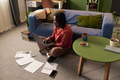Young Black Man Sitting on Floor Using Laptop and Studying Documents - PhotoDune Item for Sale
