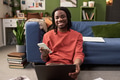 Portrait of Young Black Man Smiling While Using Smartphone and Laptop - PhotoDune Item for Sale
