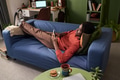 Young Black Man Relaxing on Sofa While Browsing Smartphone at Home - PhotoDune Item for Sale