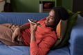 Young Black Man Relaxing on Sofa Using Smartphone Voice Assistant - PhotoDune Item for Sale