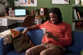 Young Black Man Relaxing on Sofa Using Smartphone in Living Room - PhotoDune Item for Sale