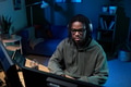 Young Black Man Wearing Headphones Coding on Computer in Home Office at Night - PhotoDune Item for Sale