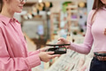 Young Woman Paying with Smartphone at Checkout Counter in Store - PhotoDune Item for Sale