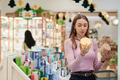 Young Woman Comparing Skincare Products While Shopping in Store - PhotoDune Item for Sale