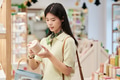 Young Asian Woman Examining Product Packaging While Shopping in Store - PhotoDune Item for Sale
