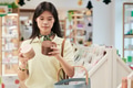 Young Asian Woman Comparing Cosmetic Products While Shopping in Store - PhotoDune Item for Sale