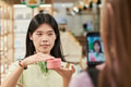 Young Asian Woman Demonstrating Cosmetic Product While Being Recorded - PhotoDune Item for Sale