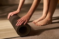 Young Woman Rolling Yoga Mat on Floor Preparing for Exercise - PhotoDune Item for Sale