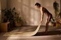 Young Adult Caucasian Woman Preparing Yoga Mat in Sunlit Home Interior - PhotoDune Item for Sale