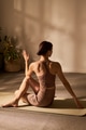 Caucasian Young Adult Woman Twisting Torso Practicing Yoga on Mat Indoors - PhotoDune Item for Sale