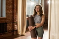 Portrait of Young Adult Caucasian Woman Smiling While Holding Yoga Mat Indoors - PhotoDune Item for Sale