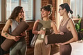 Young Adult Women Smiling While Holding Yoga Mats Indoors - PhotoDune Item for Sale