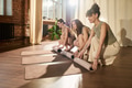 Three Young Adult Women Preparing Yoga Mats Together in Sunlit Studio - PhotoDune Item for Sale