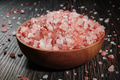 Wooden bowl filled with pink Himalayan salt crystals on dark wooden table - PhotoDune Item for Sale