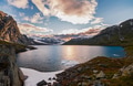 Serene Norwegian mountain lake with melting ice, snow patches and dramatic sunset clouds - PhotoDune Item for Sale
