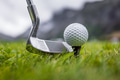 Golf club and ball on wet green field with mountains in background. - PhotoDune Item for Sale