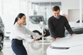 Happy young couple chooses and buying a new car for the family. Visitting the dealership - PhotoDune Item for Sale