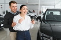 Beautiful young couple at car showroom exited because of buying a new car - PhotoDune Item for Sale