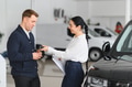 Friendly female car dealer standing at fancy car showroom and having consultations with a customer - PhotoDune Item for Sale