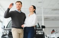 Beautiful young couple is smiling while leaning on their new car. Man is holding car keys - PhotoDune Item for Sale