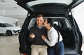 Happy young couple chooses and buying a new car for the family. Visitting the dealership - PhotoDune Item for Sale
