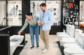 Shop assistant showing toilet to couple in bathroom furniture store - PhotoDune Item for Sale