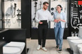 Shop assistant showing bathroom fixtures to woman in plumbing store - PhotoDune Item for Sale