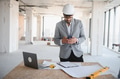 Arab architect using smartphone on construction site with blueprint and laptop - PhotoDune Item for Sale