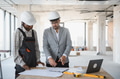 Architect and builder discussing blueprint in building under construction - PhotoDune Item for Sale