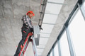 Construction worker installing ventilation system on a ladder - PhotoDune Item for Sale