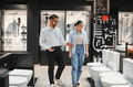 Salesman showing toilets to customer in bathroom fixtures store - PhotoDune Item for Sale