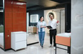 Shop assistant showing bathroom furniture to woman in plumbing store - PhotoDune Item for Sale