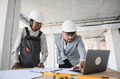 Architect showing blueprint to builder using laptop during construction - PhotoDune Item for Sale