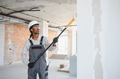 Construction worker painting wall with roller in building under construction - PhotoDune Item for Sale