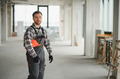 Construction worker walking in building under construction carrying helmet - PhotoDune Item for Sale