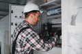 Electrician repairing electrical panel wearing protective helmet - PhotoDune Item for Sale