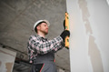 Construction worker using spirit level on wall during renovation - PhotoDune Item for Sale